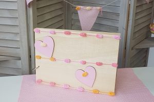 ξύλινο βιβλίο ευχών στολισμένο με ροζ ξλύλινες καρδιές και ροζ-πορτκαλί τρέσσα